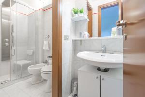 a white bathroom with a sink and a toilet at Locami Apartment Niguarda in Milan