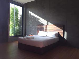 ein Schlafzimmer mit einem Bett und einem großen Fenster in der Unterkunft boomresort in Ron Phibun
