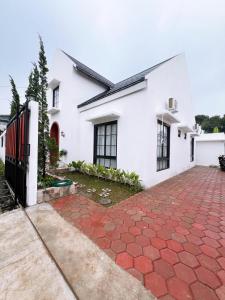a white house with a red brick driveway at Casa de Gaudete 3 Bedroom King Size Villa Lembang in Genteng