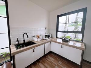a kitchen with white cabinets and a sink and a window at Casa de Gaudete 3 Bedroom King Size Villa Lembang in Genteng