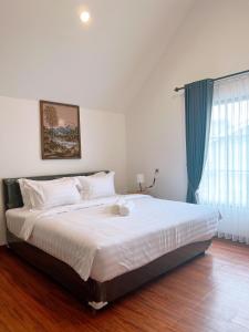 a bedroom with a large white bed with a window at Casa de Gaudete 3 Bedroom King Size Villa Lembang in Genteng