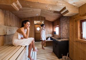 eine Frau, die am Rande einer Sauna sitzt in der Unterkunft Hotel Angelo Engel in St. Ulrich in Gröden