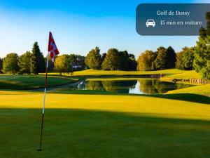 a golf course with a flag on the green at Cozy home Disney in Chalifert