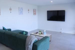 Una sala de estar con un sofá y un televisor. en Mountain-Top Ocean View in Coffs Harbour, en Coffs Harbour