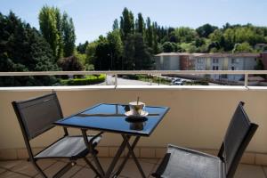 a table and two chairs on a balcony at Hotel Médicis in Roussillon en Isere
