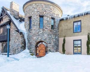 a stone house with a wooden door in the snow at Bluegreen Vacations Big Bear Village, an Ascend Collection Resort in Big Bear Lake