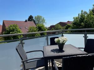 a table on a balcony with a vase of flowers at Helle Balkonwohnung Spiekeroog in Hooksiel