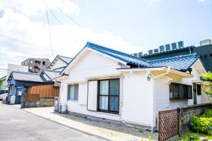 a white house with a blue roof on a street at Miraie Yokkaichi Simizucho 2 in Yokkaichi