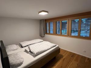 a bedroom with two beds and two windows at Larix in Ulrichen