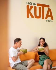 a man and a woman sitting on a couch with drinks at Lost Inn Kuta Capsule Hostel in Kuta Lombok