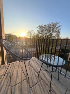 einen Stuhl und einen Tisch auf einem Balkon mit Blick auf den Sonnenuntergang in der Unterkunft Mikes Apartments Munich in München + 31 Fotos