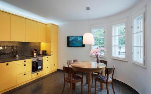 kuchnia z żółtymi szafkami oraz stołem i krzesłami w obiekcie Apartment am Hofgarten w mieście Innsbruck