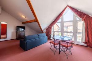a living room with a blue couch and a glass table at Zenitude Evian Les Terrasses du Lac, an Ascend Collection Hotel in Évian-les-Bains