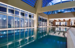 a swimming pool in a building with windows and a ceiling at Grand Millennium Al Wahda Hotel and Executive Apartments Abu Dhabi in Abu Dhabi