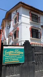 a white building with a sign on a fence at Serene by Juniper Resorts in Srinagar