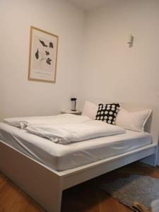 a white bed in a room with a picture on the wall at Lang's square apartment in Zagreb