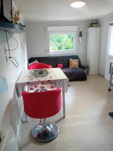 a living room with a table and a red chair at marlynn in Gérardmer