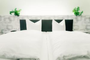 
a white bed with white pillows and pillows at Fair Hotel Mönchengladbach City in Mönchengladbach
