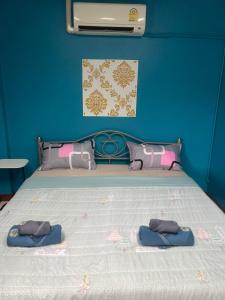 a blue bedroom with a bed with two pillows at Ciao Bella GuestHouse & Bistro in Kata Beach