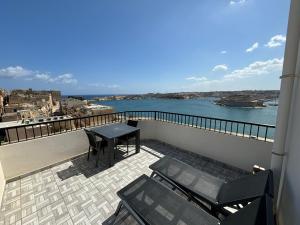 a balcony with a table and chairs and the water at Grand Harbour Hotel in Valletta