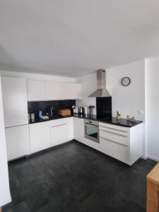 une cuisine avec des armoires blanches et une cuisinière dans l'établissement Schöne neue 2,5 Zimmer Wohnung in Savognin, à Savognin