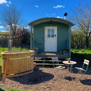 a green shed with a table and chairs in front of it at Westfield House Farm in Rothbury