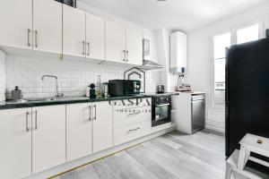 a kitchen with white cabinets and a black refrigerator at GASPAR - Appartement 2 Chambres 4 personnes Dernier étage 75 m2 in Boulogne-Billancourt