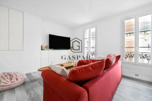 a living room with a red couch and a tv at GASPAR - Appartement 2 Chambres 4 personnes Dernier étage 75 m2 in Boulogne-Billancourt