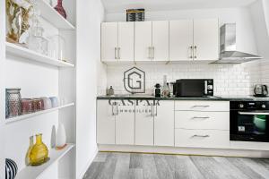 a kitchen with white cabinets and a black appliance at GASPAR - Appartement 2 Chambres 4 personnes Dernier étage 75 m2 in Boulogne-Billancourt +7 photos