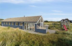 a blue house with a playground in a field at Awesome Home In Ringkøbing With Sauna in Klegod