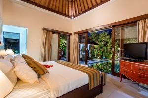 a bedroom with a large bed and a television at 6-BR Private Pool Samudra Villa Tiga Umalas 10min to Canggu Beach in Umalas