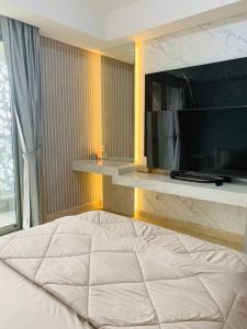 a bedroom with a large bed and a television at Apartment Goldcoast-Studio Room in Jakarta +18 photos