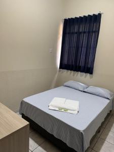 a bedroom with a bed with two towels on it at Hotel Vila Rica in Maringá