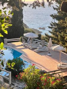 Una piscina con sillas y sombrillas junto al mar. en Myrto Homes Lefkada Agios Nikitas Greece, en Agios Nikitas