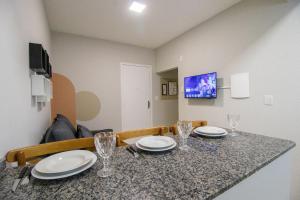Una mesa de comedor con platos y vasos encima. en JOA23 - 1 Dorm, Climatizado, Garagem, TV Smart, en Balneário Camboriú