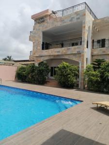 a villa with a swimming pool in front of a house at Belle location familiale in Abomey-Calavi