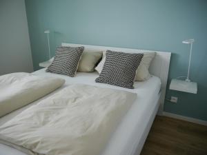 a bedroom with two beds with white sheets and pillows at Panoramablick Ostsee, Binnensee & Salzwiesen - Balkon - Stilvoll - Highspeed Glasfaser WLAN - Parkplatz - Ferienwohnung 'Freiheit' in Heiligenhafen