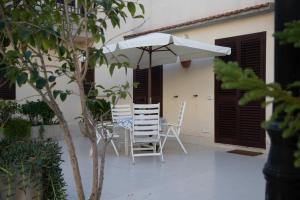 a patio with two chairs and an umbrella at Casa Kaukana - A Pochi Passi dal Mare in Villaggio Azzurro