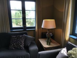 a living room with a chair and a lamp and two windows at Maltes Hüs in Braderup +11 photos