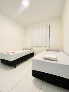 two beds in a white room with a window at Ap da Thay - Arretado in Campina Grande