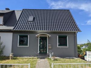 Hoffmanns Eden Ferienhaus في هيرمسكايل: منزل رمادي صغير مع باب أخضر