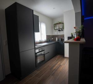 a kitchen with a large black refrigerator and wooden floors at LA NUIT DES SECRETS Love Room 4 étoiles avec Jacuzzi et Sauna in Roquebrune-sur-Argens