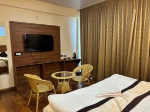 a hotel room with a bed and a tv and chairs at Deolo Mist - A Boutique Mountain Hotel in Kalimpong