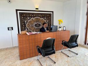 a man sitting at a desk with a computer at Deolo Mist - A Boutique Mountain Hotel in Kalimpong