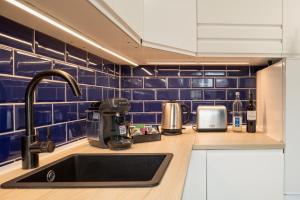 a kitchen with blue tiled walls and a sink at Boardinghouse Hohenzollern in Berlin