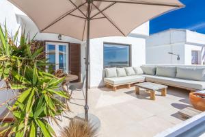 patio z kanapą i parasolem w obiekcie Los Lances Beach Apartments w mieście Tarifa