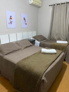 a bedroom with two beds and a window at Pousada dos Pássaros in Gramado