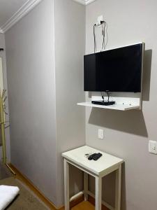 a television on a shelf on a wall with a table at Pousada dos Pássaros in Gramado