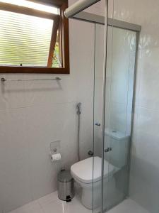 a bathroom with a toilet and a glass shower at Pousada dos Pássaros in Gramado