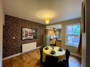 a dining room with a table and a brick wall at Stylish 3-Bedroom Home! in Bedworth
